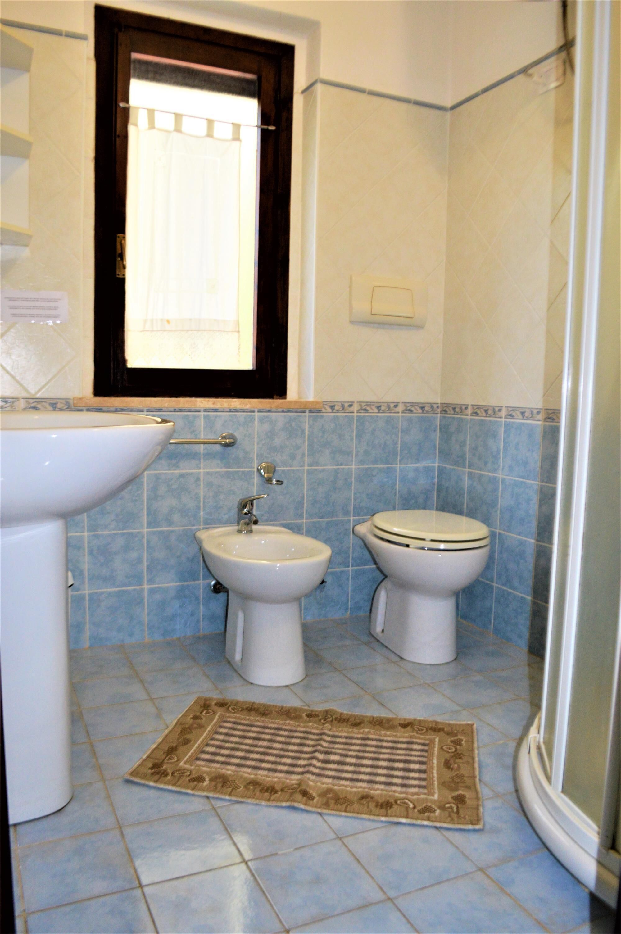 A bathroom with a sink, bidet, toilet, and a shower area.