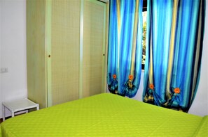 Um quarto com uma cama, uma mesinha e um guarda-roupa.