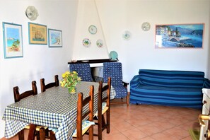 Uma sala de jantar com toalha xadrez, cadeiras de madeira e sofá listrado em azul.