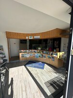 A reception desk with a welcome sign, wooden paneling, and a bulletin board with various notices.