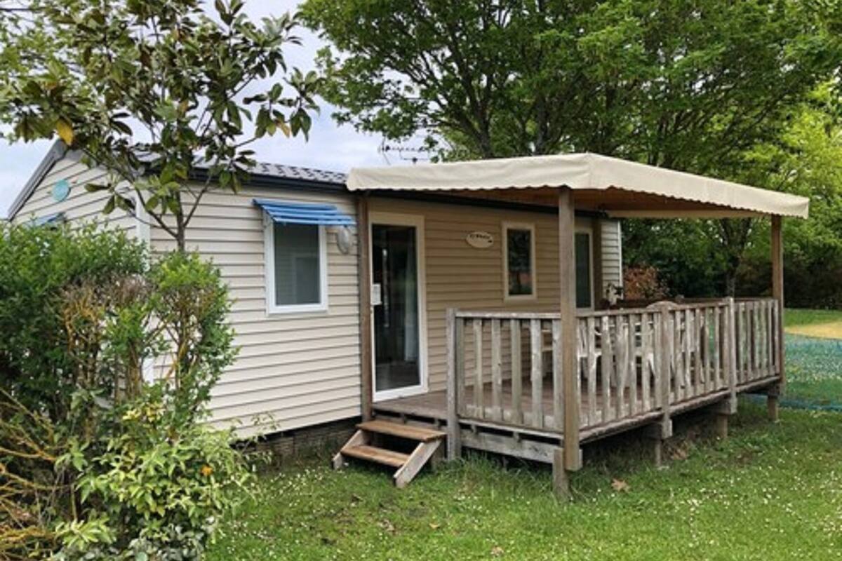 A small, single-story cabin with a wooden deck and a covered porch.