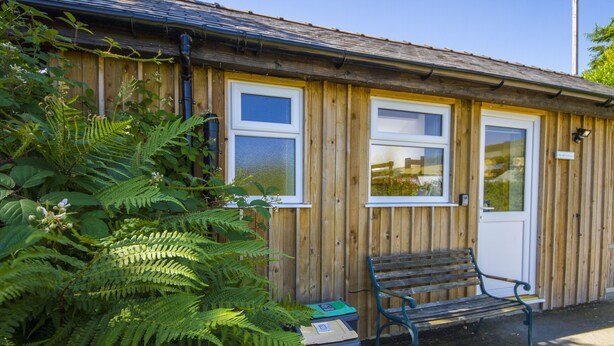 A wooden building with windows and a bench outside. - The Little Bunk House (Oswestry)