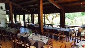 Un restaurante con varias mesas preparadas para comer, sillas de madera y piso de baldosas.