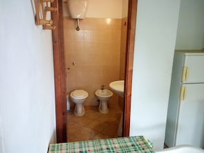 A small bathroom with two toilets, a sink, and a toilet paper holder on the wall. - Villaggio Mediterraneo (Scalea)