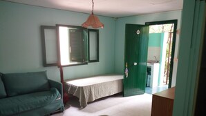 A room with a bed, a sofa, a hanging light fixture, and a door leading to a bathroom. - Villaggio Mediterraneo (Scalea)