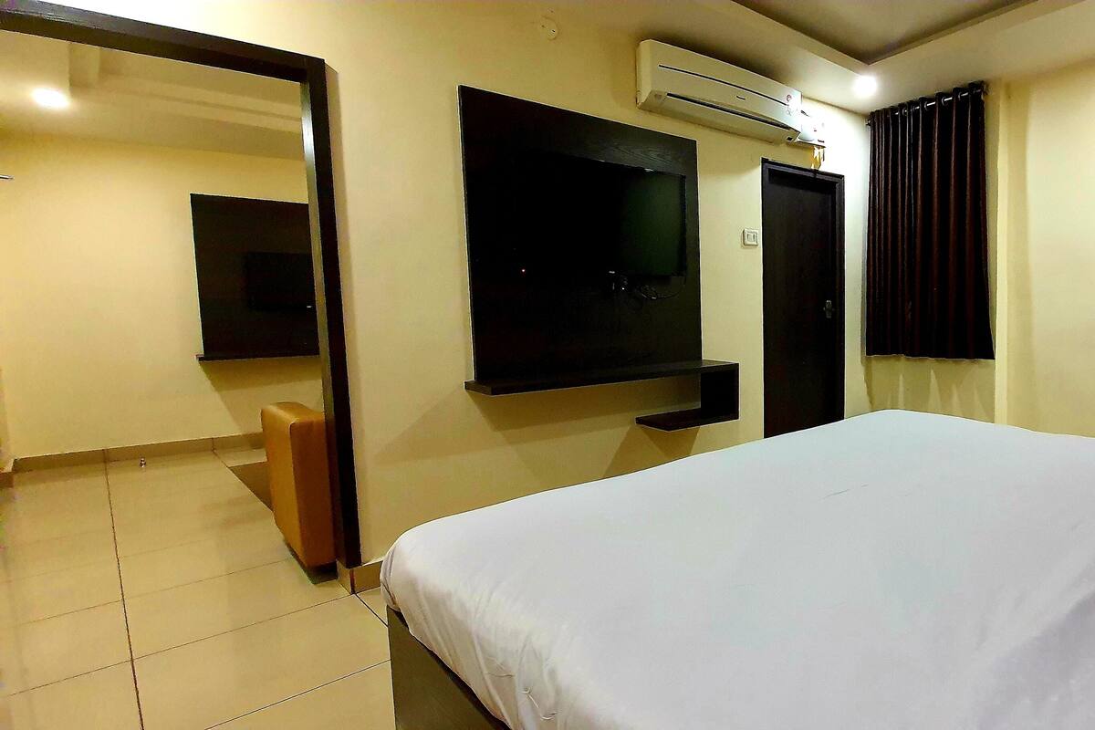 Ein Hotelzimmer mit Bett, Wandfernseher, Tür und Klimaanlage.