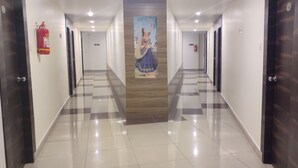 Un couloir d’hôtel avec un sol à carreaux, des lambris en bois et un extincteur fixé au mur.