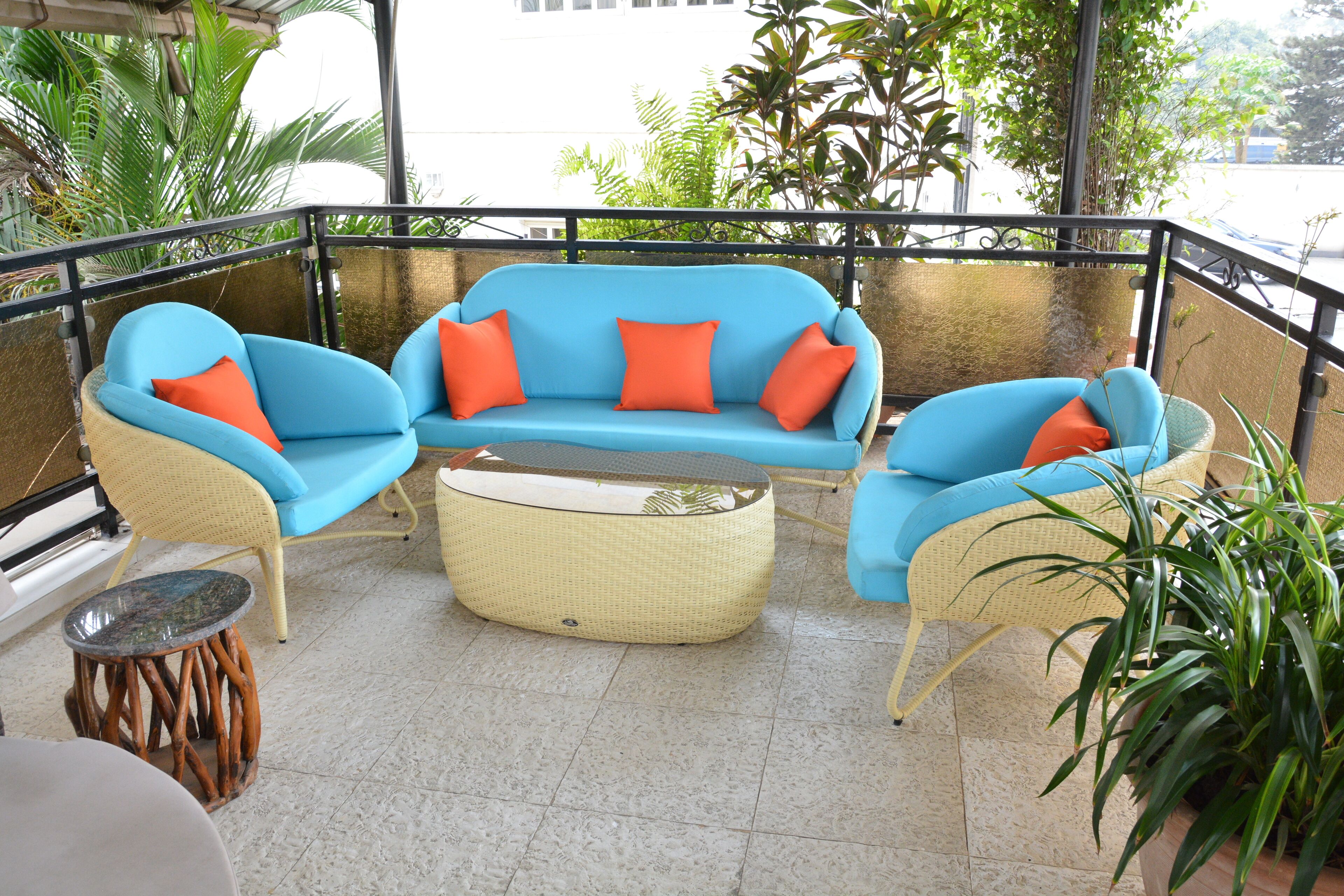 A balcony with wicker furniture, including a sofa and chairs, and a small round table.