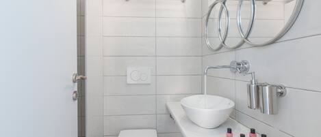Un baño moderno con inodoro, lavamanos, toallero y espejo.