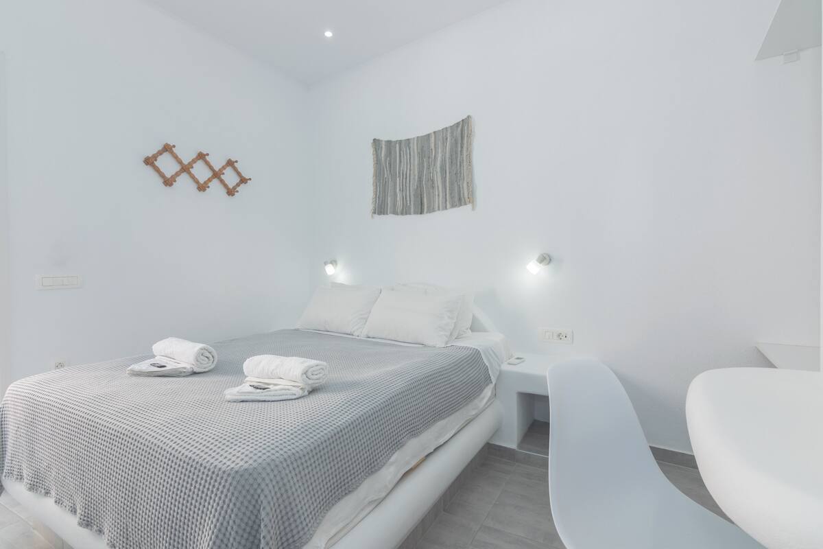 Quarto moderno com cama bem arrumada, mesa de cabeceira com abajur e uma peça de arte de parede única.