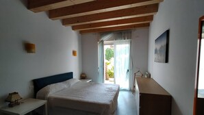 A bedroom with a bed, a desk, a dresser, and a door leading to a balcony. - Rome beach house (Fiumicino)