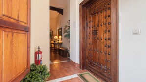 A wooden door with a metal grille, a fire extinguisher, and a small potted plant. - Córdoba Cool  Homes Vailima (Cordoba)