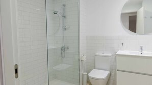 A modern bathroom with a glass-enclosed shower, a toilet, and a sink.