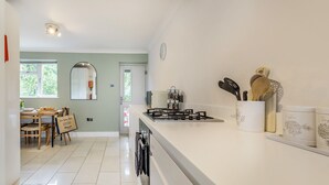 Una cocina moderna con estufa a gas, encimeras blancas y una zona de comedor con mesa y sillas.