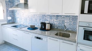 A kitchen with white cabinets, a stainless steel sink, and a coffee maker on the counter. - Cordobacourt la Ribera (Cordoba)