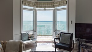 Een woonkamer met uitzicht op zee, een televisie en een bord waarop staat 