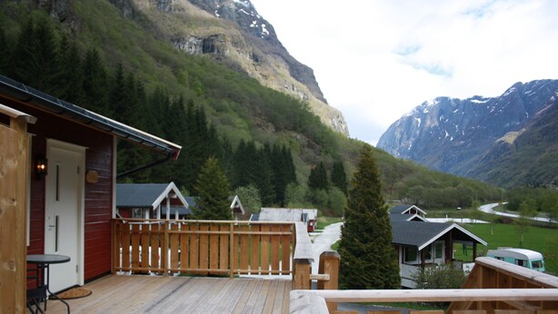 A wooden deck with a view of a mountain and a small building. - Gudvangen Camping (Aurland)