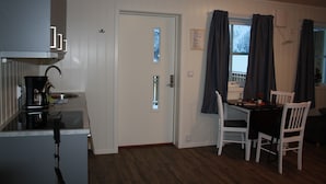 A compact kitchen with a coffee maker, a sink, and a dining area with a table and chairs. - Gudvangen Camping (Aurland)