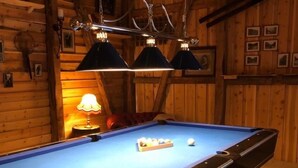 A pool table in a wooden room with hanging lamps and framed pictures on the wall. - Gudvangen Camping (Aurland)