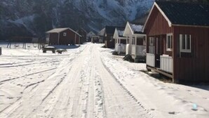 A snow-covered road with buildings on the right. - Gudvangen Camping (Aurland)