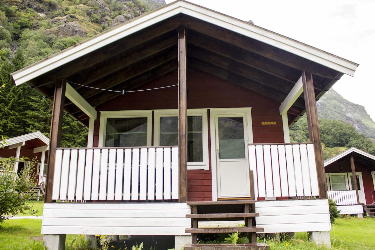 A cabin with a porch, a door, and a window.