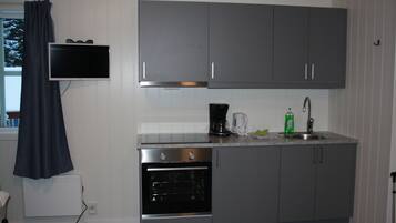 A compact kitchen with grey cabinets, a built-in oven, a coffee maker, and a sink.