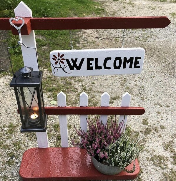 Un cartel de bienvenida con un farol y una planta en maceta.