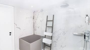 A modern bathroom with a marble wall, a bathtub, a shower, and a wooden ladder shelf.