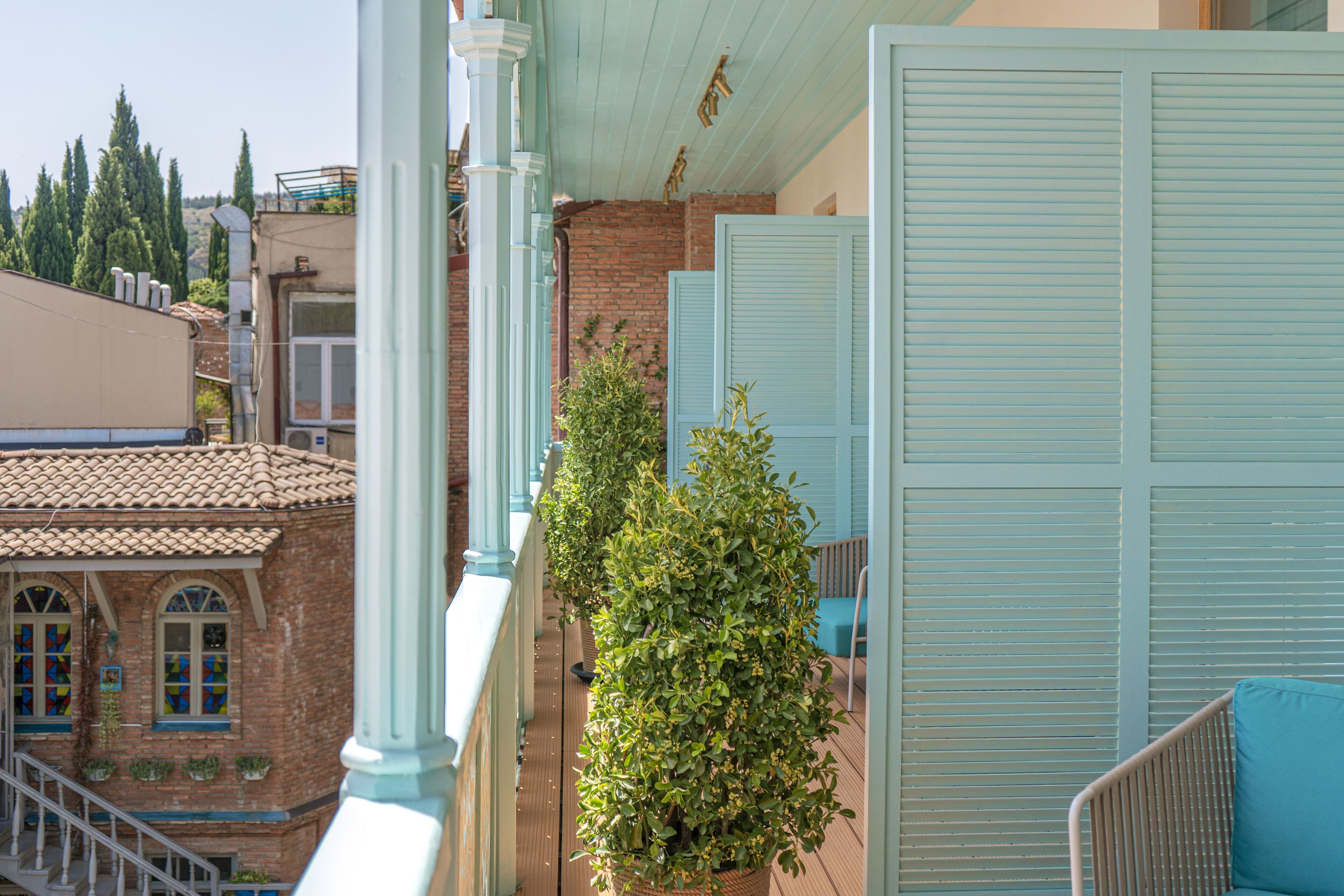 Ein Balkon mit Blick auf ein Backsteingebäude, einem Blumentopf und einem blauen Stuhl.