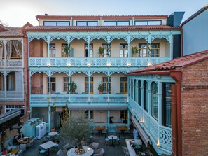 A courtyard with outdoor seating, a central tree, and a building with ornate balconies. - The Blue Fox Hotel (Tbilisi)