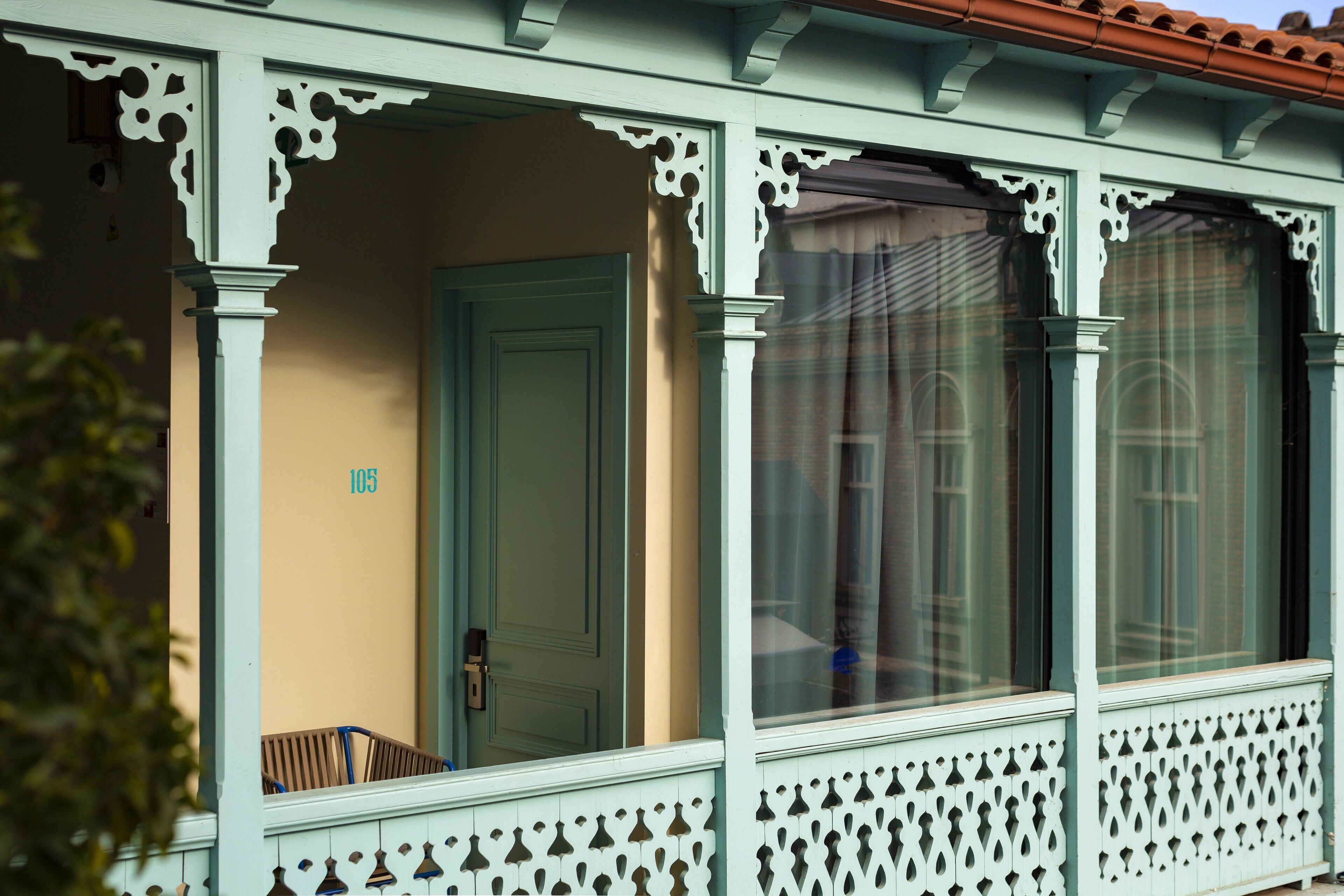 A building with a porch featuring decorative white railings and a door marked with the number 105.