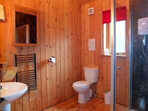 Un baño con paneles de madera, que incluye inodoro, lavamanos y ducha.