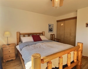 A wooden bed with a headboard, a bedside table with a lamp, and a wardrobe.