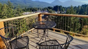 A balcony with a table and chairs, offering a view of a forested mountain range. - `Elk Ridge` | Hot tub, Wifi, Roku, Close to town. (Packwood)