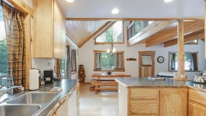 Una cocina moderna con armarios de madera, un lavamanos y una zona de comedor con bancos.