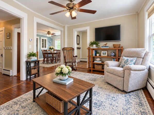 A living room with a sofa, a coffee table, a TV, and a ceiling fan.
