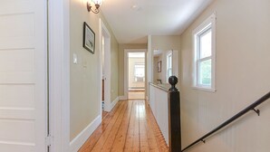 Un couloir doté d’un plancher en bois, de murs blancs et d’une balustrade noire.