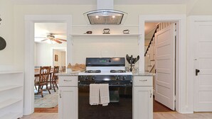 Une cuisine de taille réduite, dotée d’un four encastré, d’une cuisinière à gaz et d’un ventilateur de plafond.