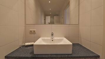 A bathroom with a white sink, dark granite countertop, and wooden cabinets.