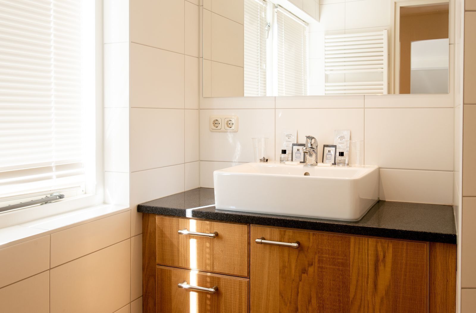 A bathroom with a white sink, wooden cabinets, and a mirror above the sink.