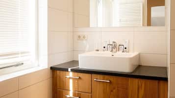 A bathroom with a white sink, wooden cabinets, and a mirror above the sink.