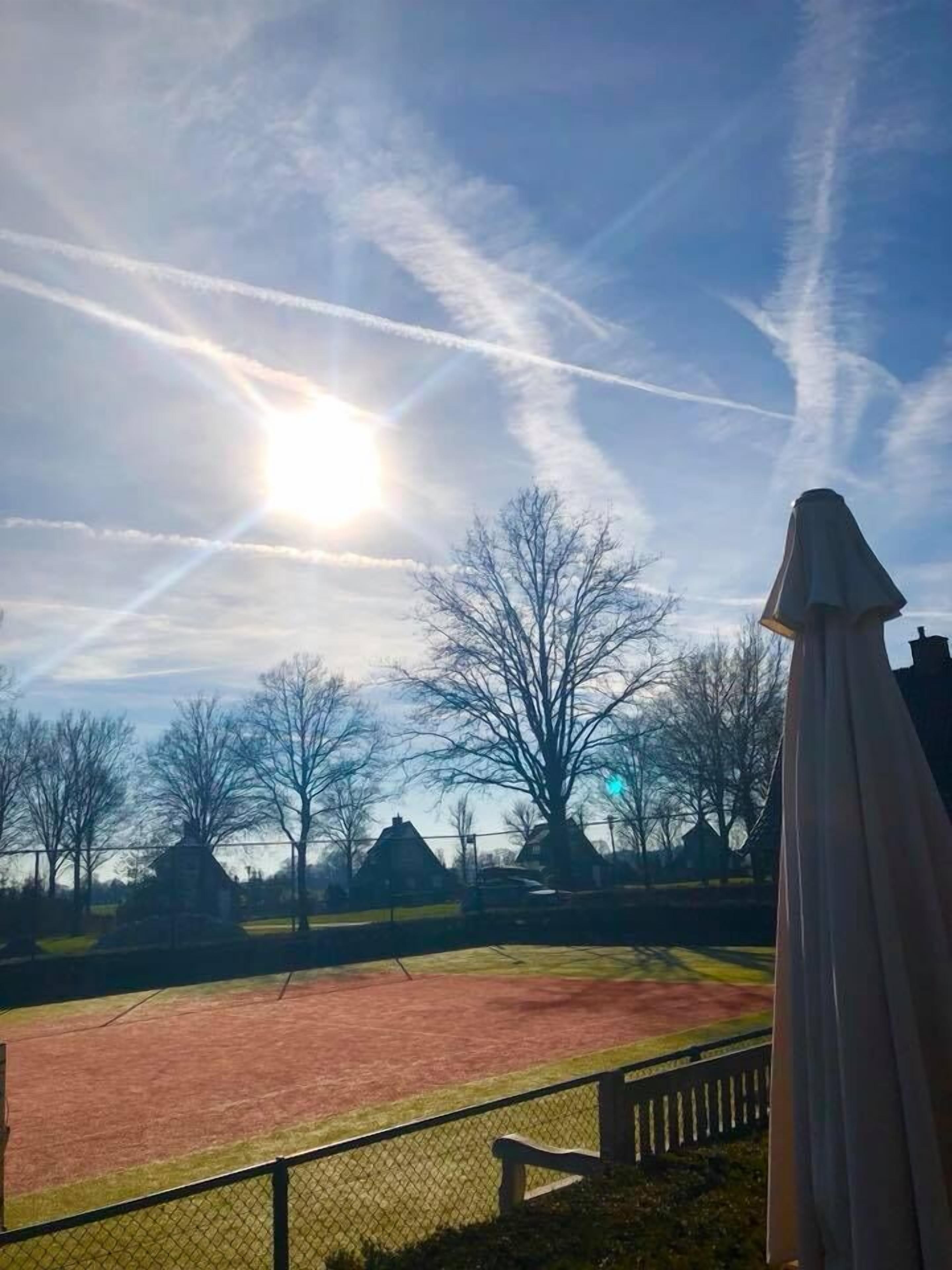 A sports field with a clear sky and a sun shining.