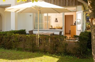 Uma casa moderna com um pátio, uma mesa de jantar e cadeiras.