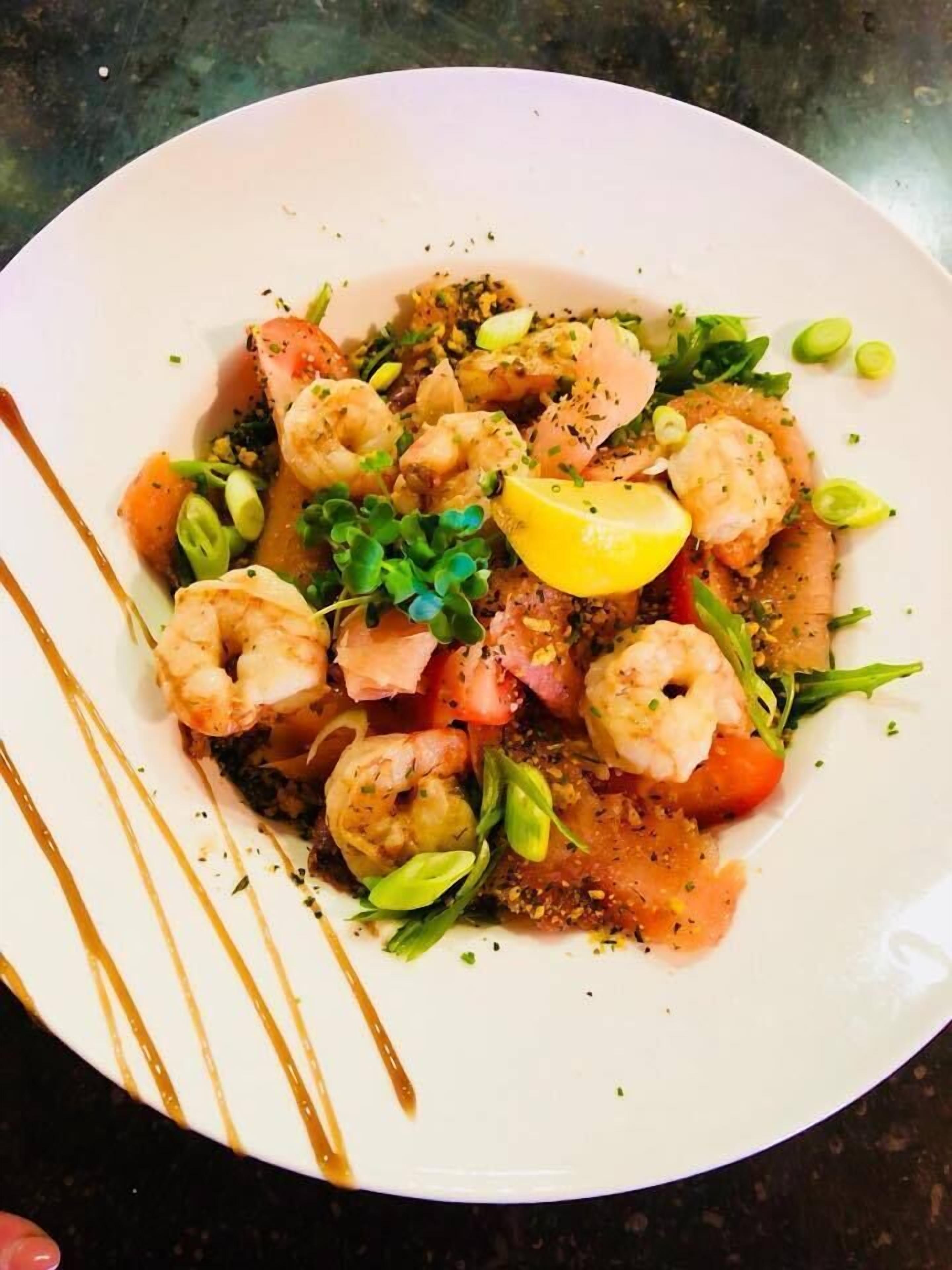 A plate of food with shrimp, lemon, and greens.