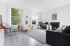A modern living room with a fireplace, a dining area with a table and chairs, and a workspace with a desk and computer. - Well Presented one Bedroom Apartment Located in the Fabulous Notting Hill (London)