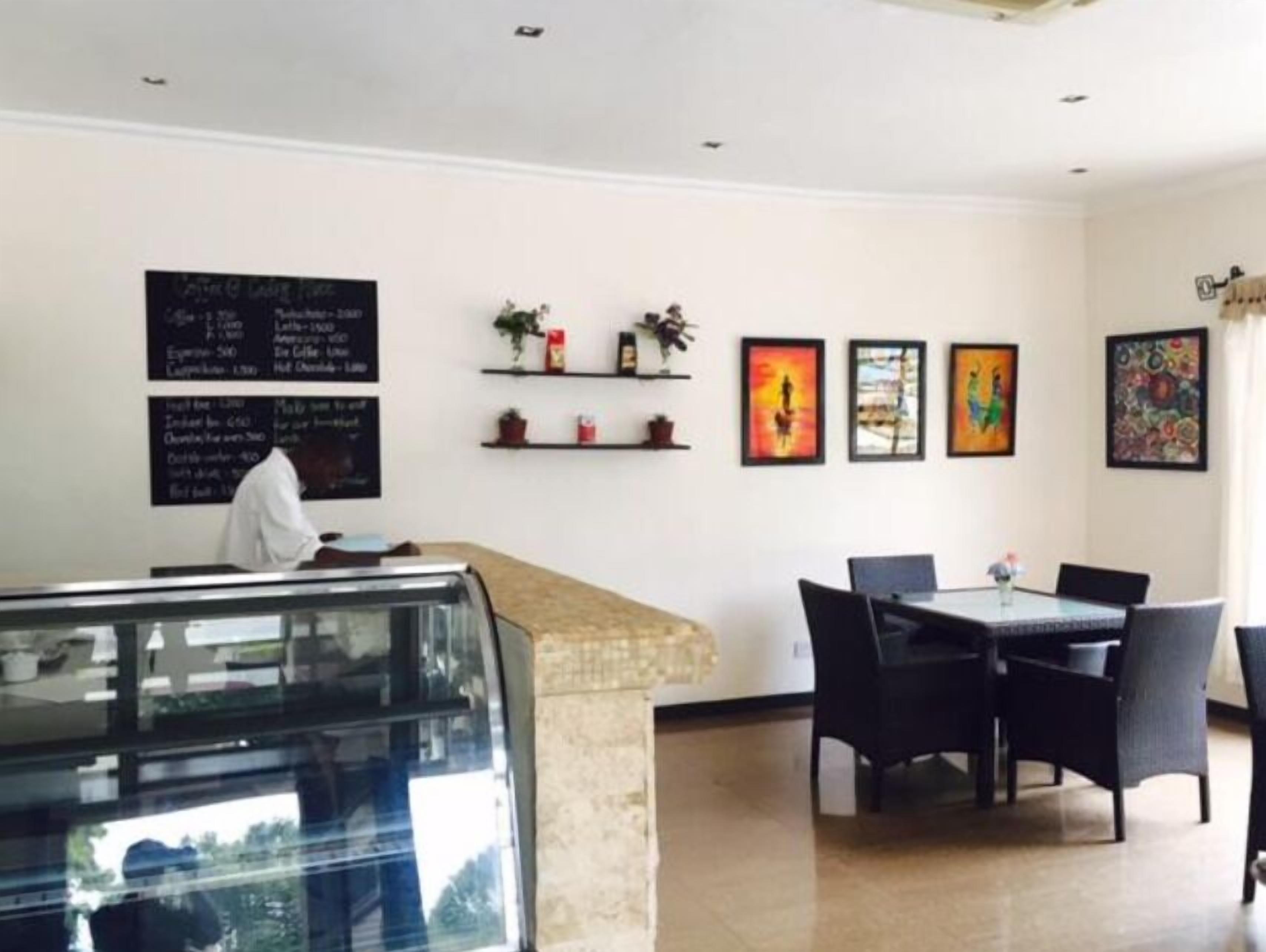 A restaurant interior with a counter, menu boards, artwork, and seating area.