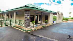 A building with a green roof, a covered entrance, and a staircase leading to a door. - Cedar Place (Blantyre)