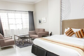 Una habitación de hotel moderna con una cama grande, un sofá, una mesa de centro y un escritorio.