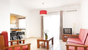 Una sala de estar con sofá, una mesa de centro, televisor y un comedor con sillas y una mesa.