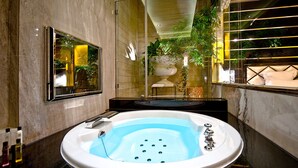 Un baño moderno con una bañera grande, un espejo y una planta en maceta.